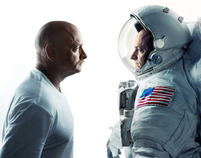 Mark and Scott Kelly face each other, one in a t-shirt, one in a space suit