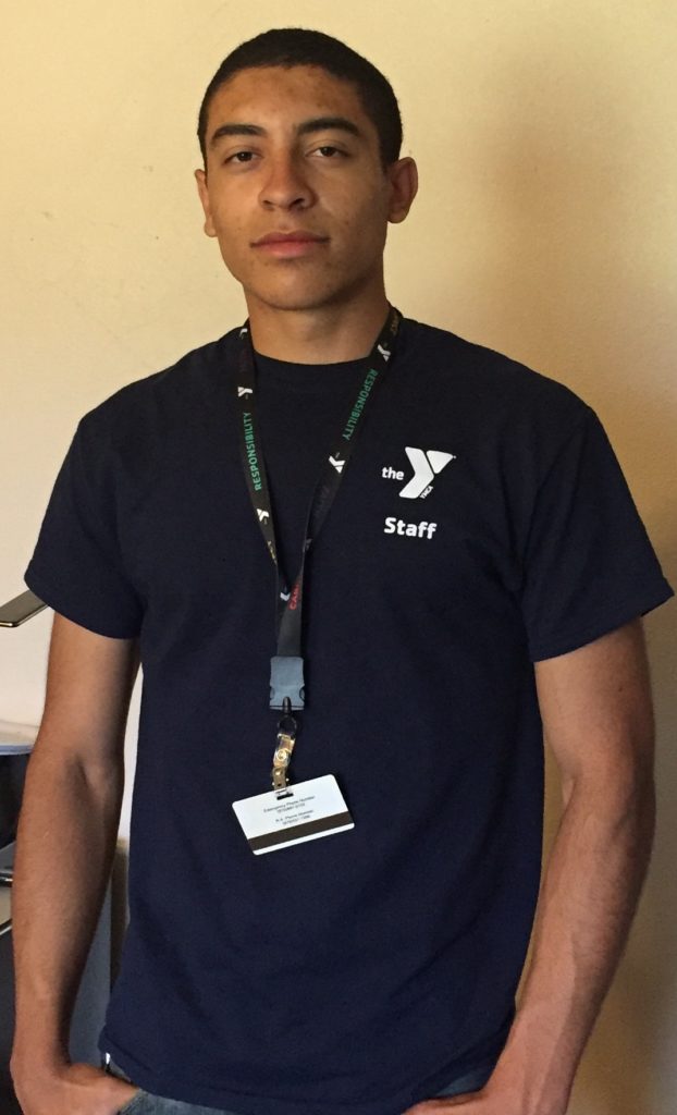 Zach posing in YMCA uniform and badge
