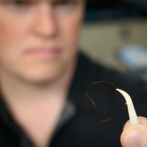 Brian Geiss holds a piece of fine wire used in his research