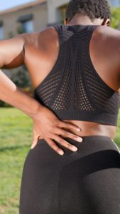 a woman having back pain, her hand on her lower back