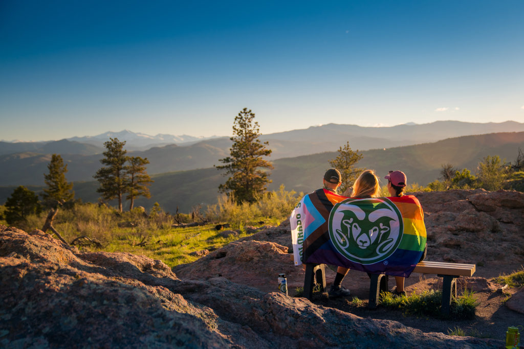 people on a mountain with a CSU and rainbow flag