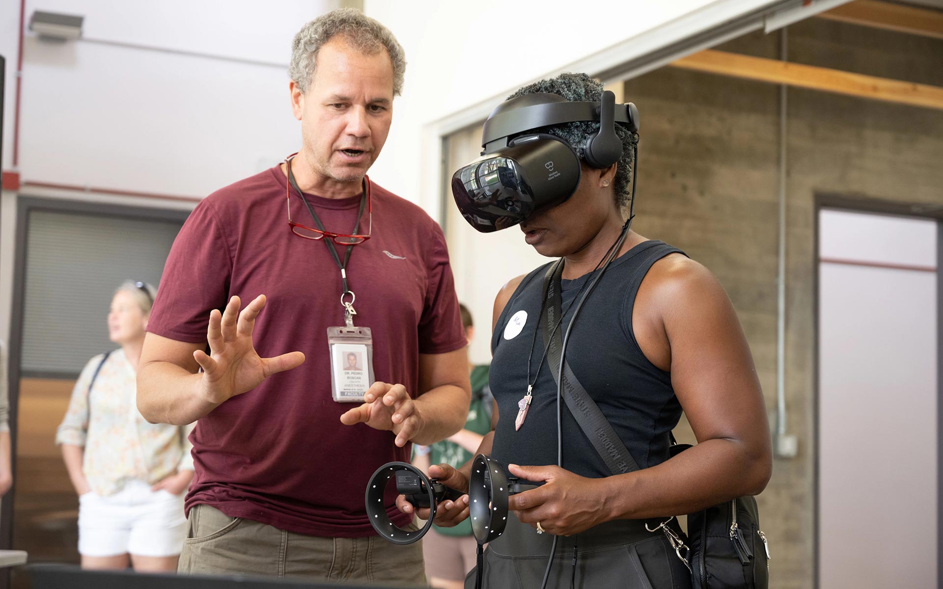 Faculty member Pedro Boscan coaches a user wearing a virtual reality headset